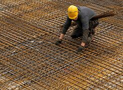 Worker tying steel reinforcement mesh before a concrete pour