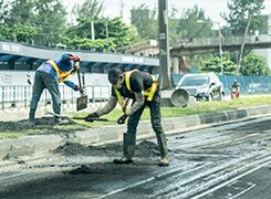 Labourers spreading asphalt by hand during road resurfacing